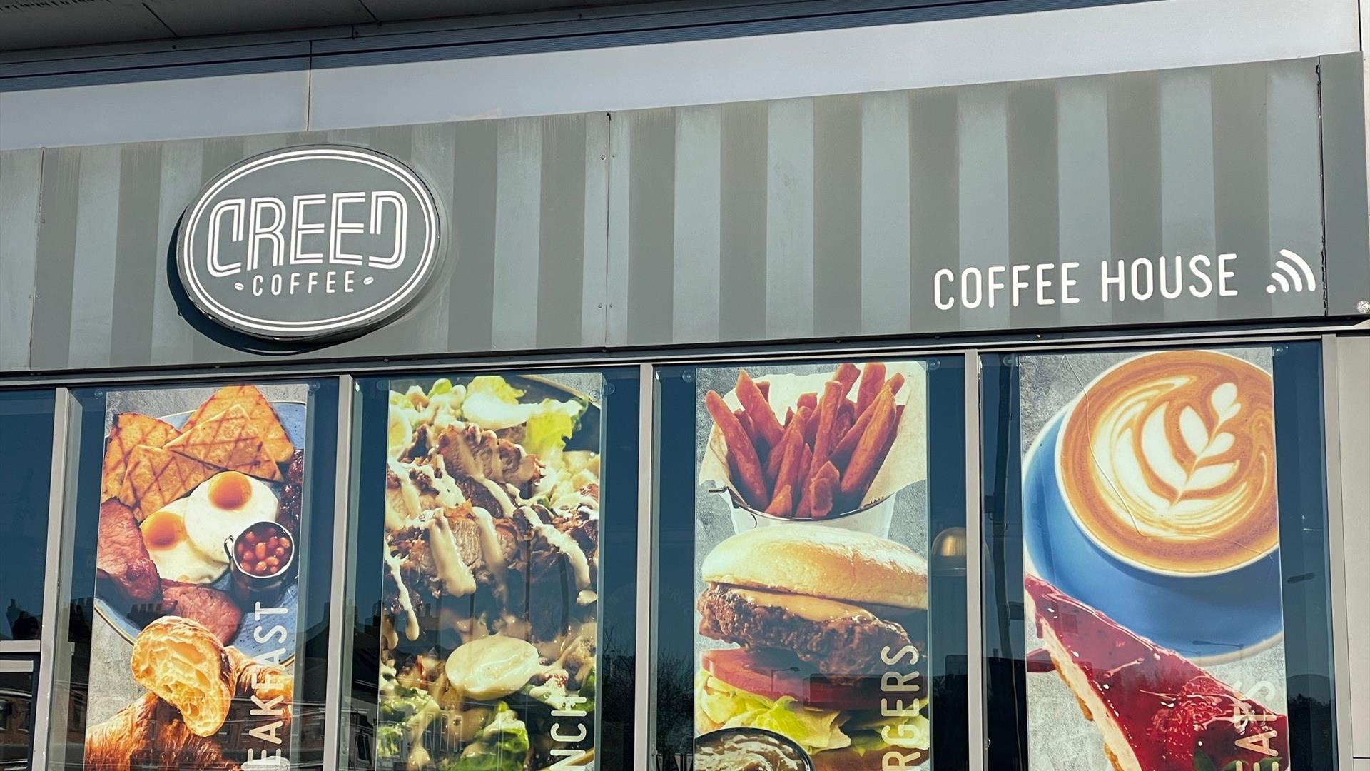 Exterior of Creed Coffee House in Carrickfergus with banners in windows displaying food options