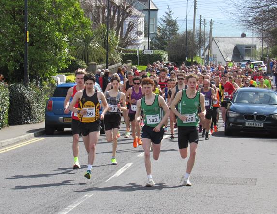 Pack of competitive runners running down street in Whitehead as part of Whitehead Road Race