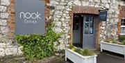Brick exterior of Nook Living with grey signage and white planter