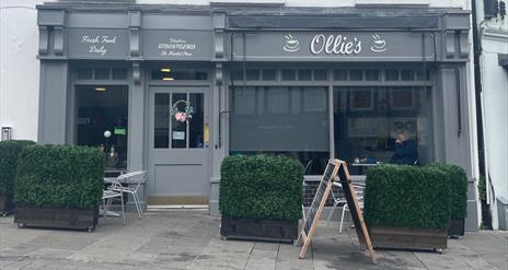 Exterior of Ollie's Bistro, Carrickfergus with grey exterior and outdoor seating area with hedge surround