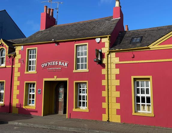 Pink and yellow exterior of Ownies Bar in Carrickfergus
