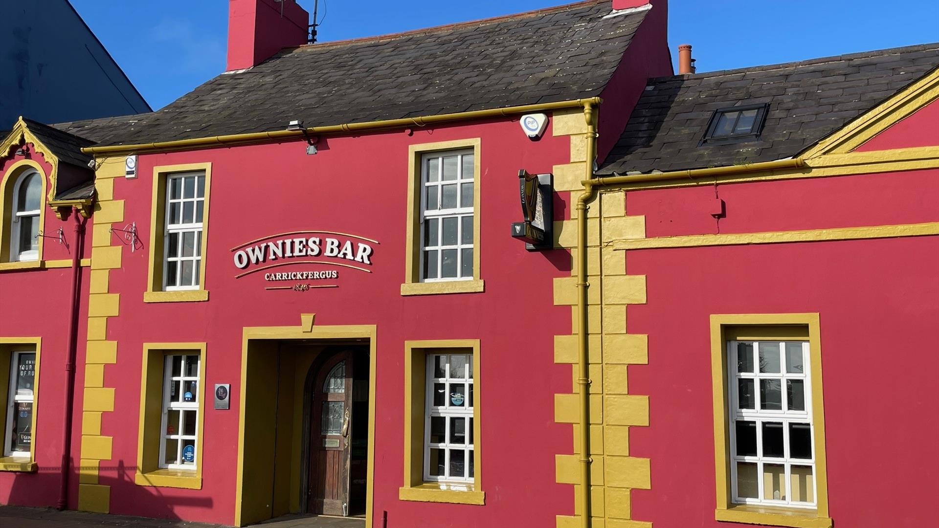 Pink and yellow exterior of Ownies Bar in Carrickfergus