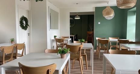 Seating area within Quarter House Coffee - white tables with wooden seats and green painted walls