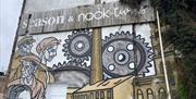 Wall mural for Season & Nook Living in Carrickfergus which links to its heritage of being a former mill featuring mill workers and machine cogs