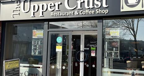 Exterior of Upper Crust restaurant and coffee shop with entrance doors and windows