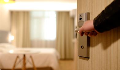 Stock image of a hotel room door being opened into the room.
