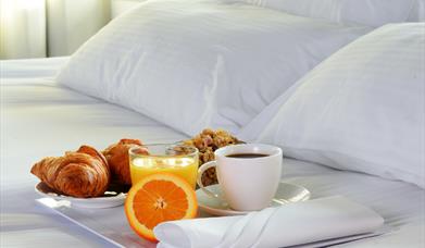 Stock image of breakfast sitting on a tray on a bed