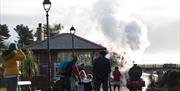 Steam train departing from Whitehead Station with family onlooking from platform