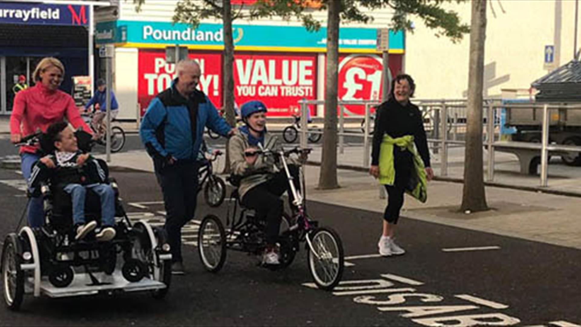 People on the street and young people using adapted bikes