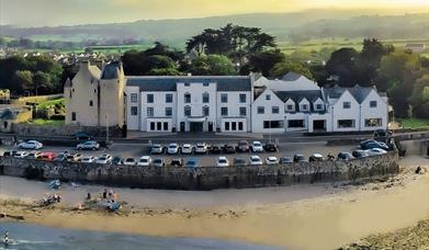 View of Ballygally Castle Hotel from the air in front of the beach.