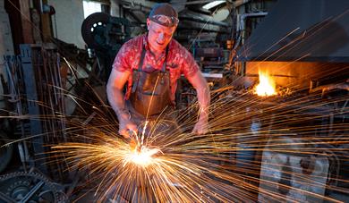 Blacksmith working in forge with sparks flying
