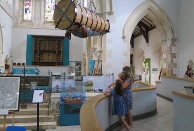 Photograph showing the main museum space with one adult and two children stood on a ramp looking up at the replica John Lethbridge Diving Engine
