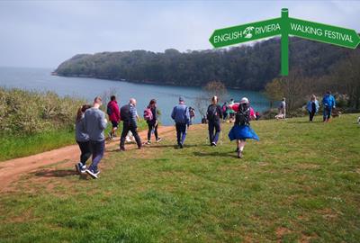 A group of people walking along the South West Coast Path between Paignton and Brixham.