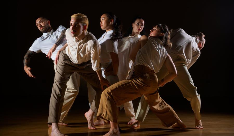 A huddle of people wearing earth tones moves in different directions