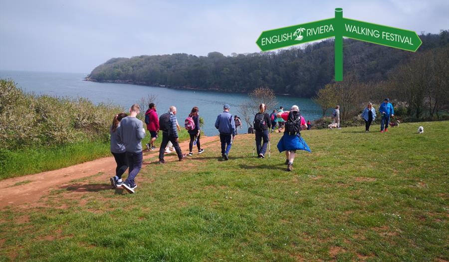 A group of people walking along the South West Coast Path between Paignton and Brixham.