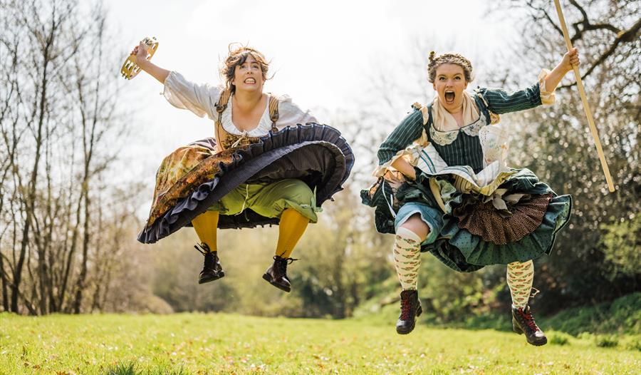 Two actresses in costume jumping in the air