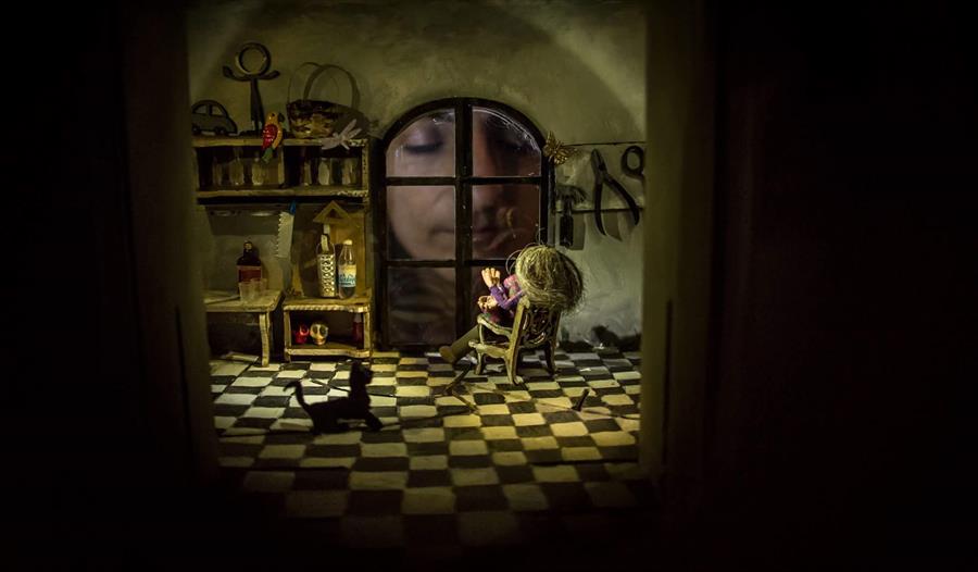 A puppet show with the puppeteer looking through a window