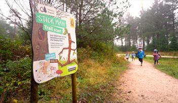 Children run towards a Stick Man activity trail panel