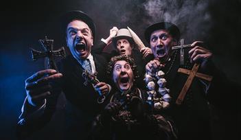 Dracula: The Bloody Truth by Le Navet Bete. Four performers stare at the camera holding garlic, crucifixes and a stake, all looking terrified.
