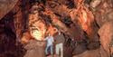 Two adults stand in one of the underground caves at Kents Cavern Prehistoric Caves in Torquay, English Riviera.