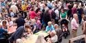 Crowds of people sitting and eating on Fore Street in Bovey Tracey enjoying the food and drinks stands at Nourish Festival