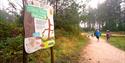 Children run towards a Stick Man activity trail panel