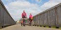 Couple cycling on a wooden bridge along the Exe Estuary Trail