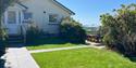 This image shows the front entrance porch and pathway to Little Byfield and the fully enclosed private garden. There is a spacious lawn in the image,
