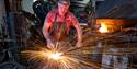 Blacksmith working in forge with sparks flying