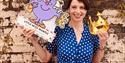 Storyteller in a blue dress, holding a cut out of Little Miss Marple and a crown