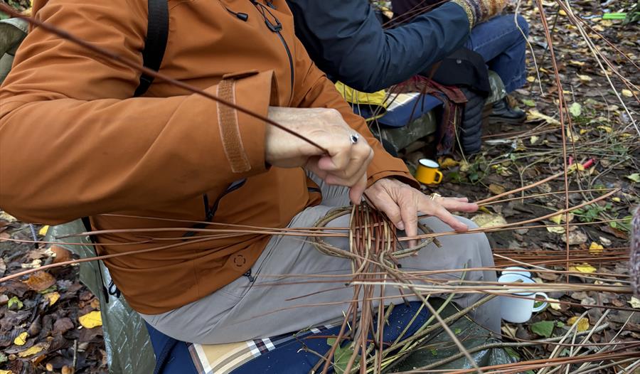 People weaving willow platters in a woodland glade People weaving willow platters in a woodland glade