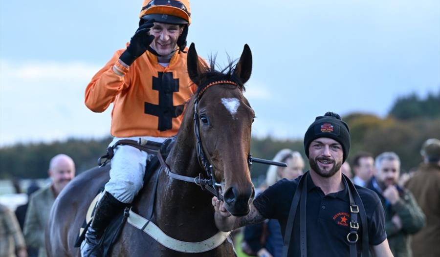 A smiling jockey and racehorse return from the track during an exciting afternoon of jump racing at Exeter Racecourse A smiling jockey and racehorse return from the track during an exciting afternoon of jump racing at Exeter Racecourse