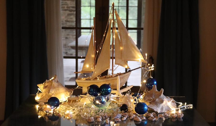 Wooden model sailing boat decorated with fairy lights, shells and baubles