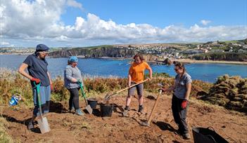 Photo of dig volunteers at Bolt Tail with sea and Hope Cove in background