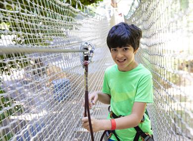 Child clipped on and taking part on the Go Ape tree top challenge course at Go Ape Crawley in West Sussex