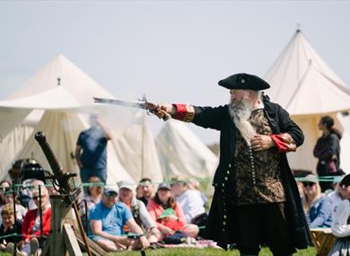 man in georgian clothes holding pistol in demonstration