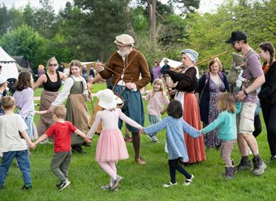 visitors dancing in a circle around a tudor reenactor