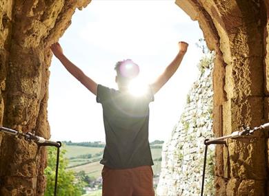 Man standing in arch of Carisbrooke Castle looking at the view, historic attraction, family fun, children's activities, summer event, what's on, Isle 