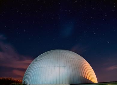 A domed planetarium beneath a clear, star-filled night sky