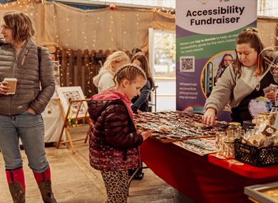 girl looking at stall in christmas market, with twinkling fairy lights in the background