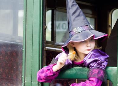 Girl dressed up as a witch looking out of the carriage window at the Wizard Week event, Isle of Wight Steam Railway, what's on