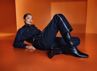 Female model dressed in denim surrounded by an orange backdrop  