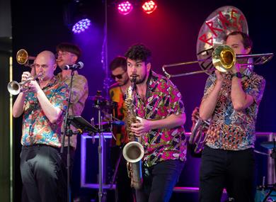 Image: The Concertini with Brass Monkeys performing on stage with brass instruments 