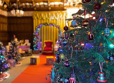 The ballroom at Bletchley Park decorated for Christmas with Christmas trees, toys, presents and a chair for Father Christmas