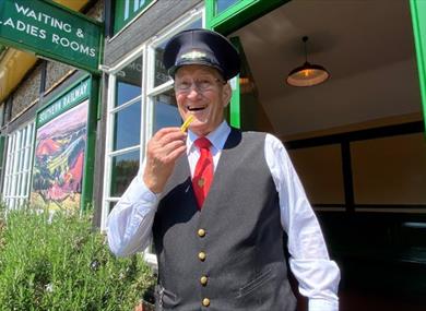 Conductor eating a chip at the Fish and Chip Evenings at Isle of Wight Steam Railway, Wootton, summer event