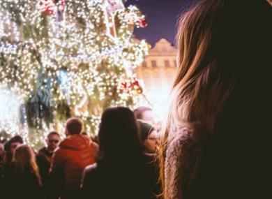Person looking up at decorated outdoor Christmas tree