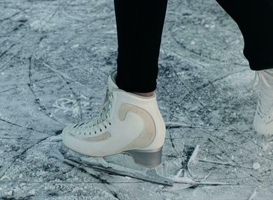 Person in white figure skates on fresh ice