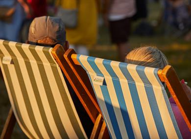 Two people sat in a deckchair at a summer event