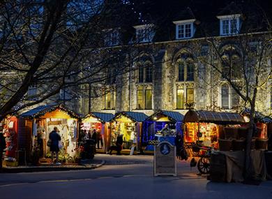Winchester Cathedral Christmas Market chalets, with Winchester Cathedral in the background at night.