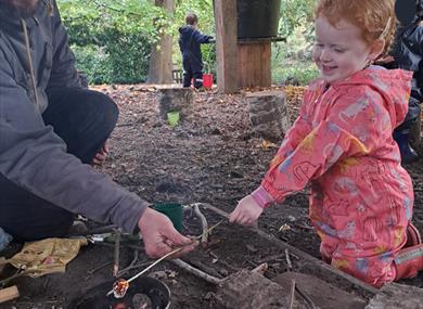 Child at campfire toasting marshmallows at Painshill